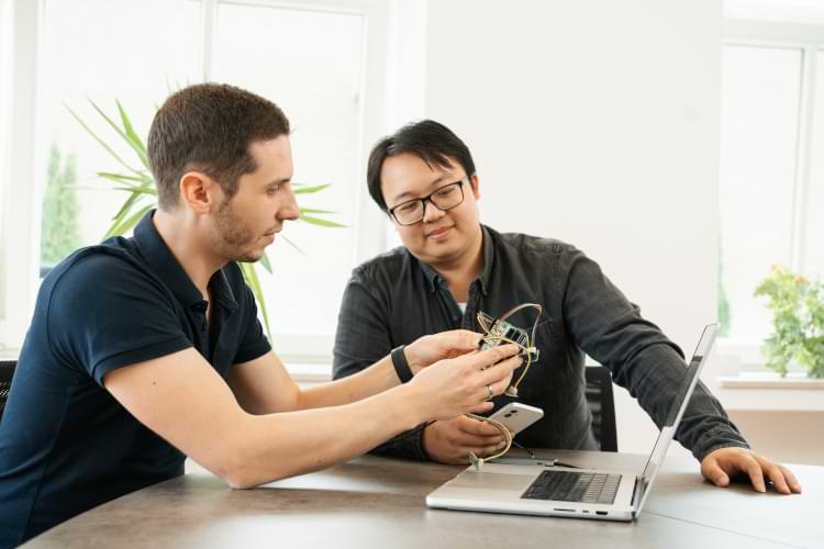 Zwei Männer betrachten vor einem Laptop ihre Arbeit